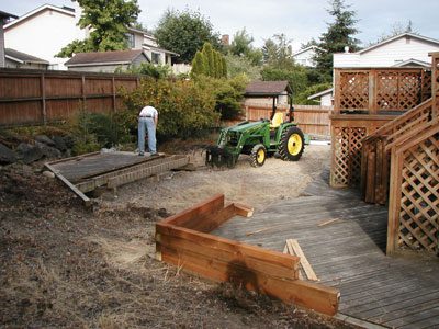 A man is working on a wooden deck in a backyard, providing efficient and professional deck removal services.