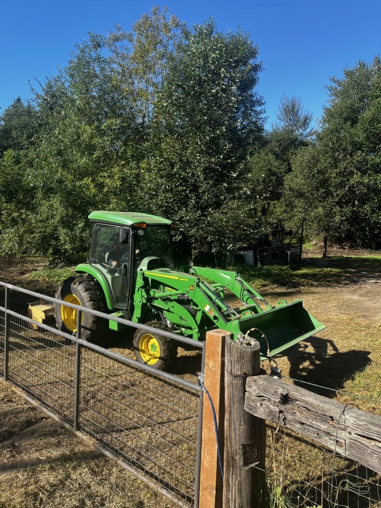 A green tractor parked next to a fence. 
Keywords: Garden services.