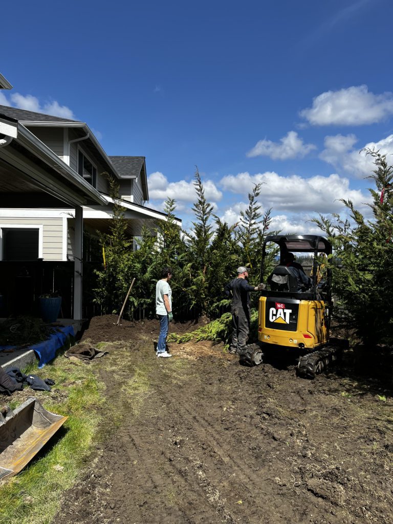 A professional is operating a bulldozer in front of a house for tree maintenance.
