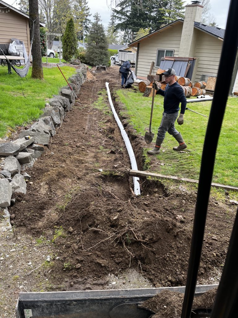 A man is working on a pipe in a yard.