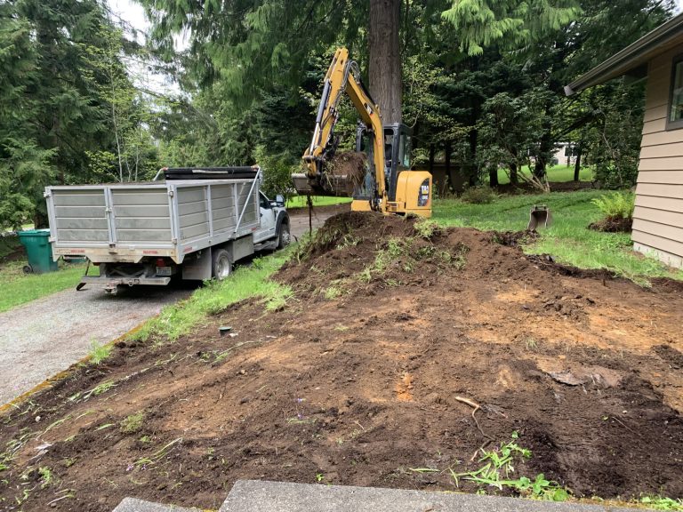 An excavator is performing grading and leveling services by digging a hole in a yard.